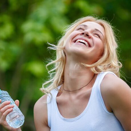 Portrait of young beautiful laughing woman with bottle of water young woman smiling holding water bottle