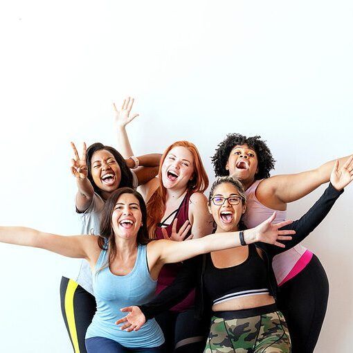 Group of happy sportive women with a white wall group of happy supportive women