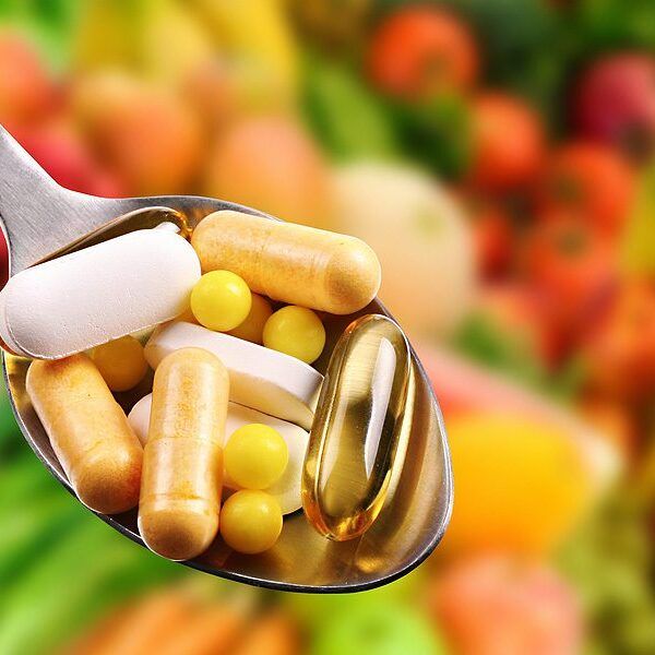 spoon with dietary supplements on fruits background